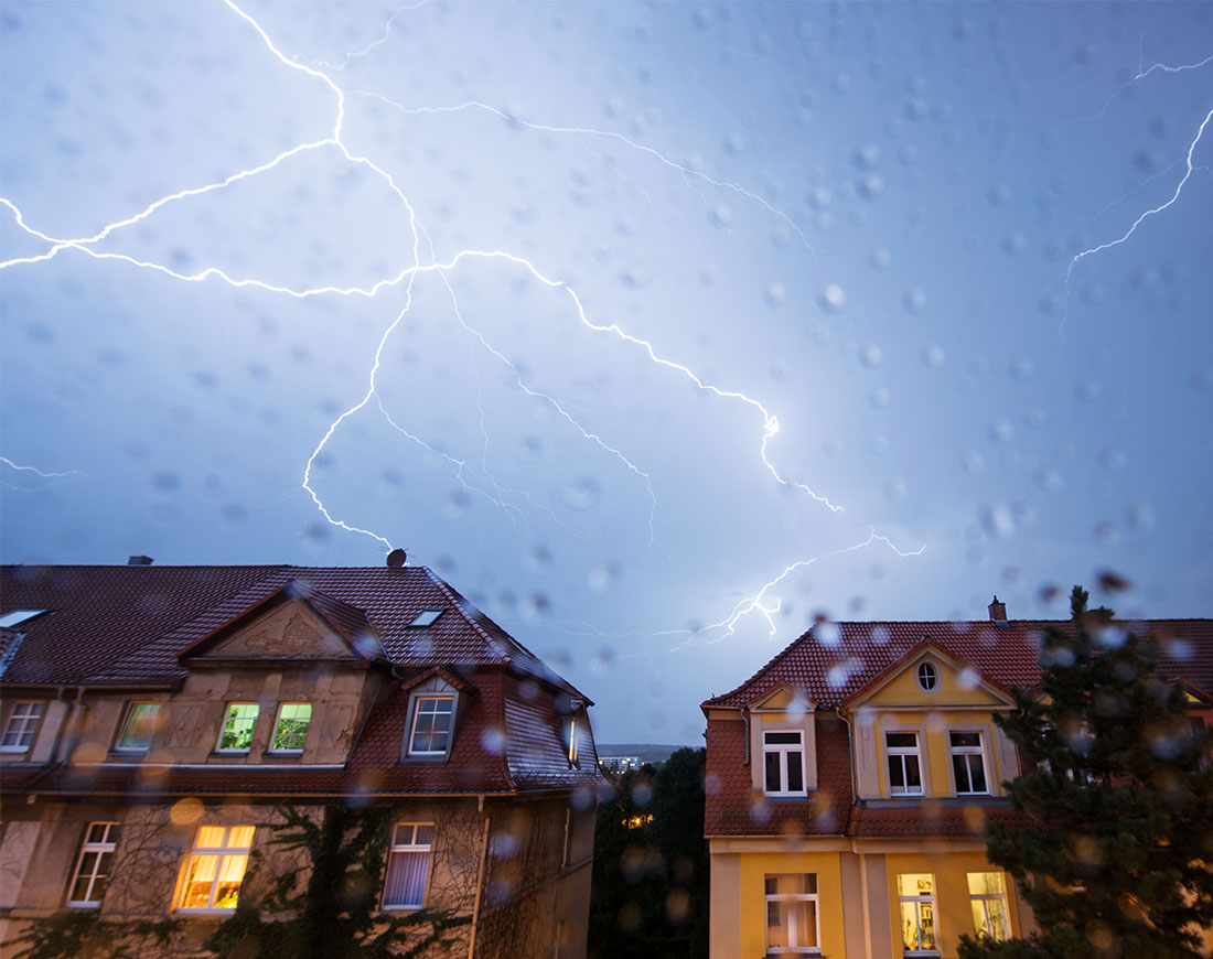 Blitze am Himmel über Wohnhäusern